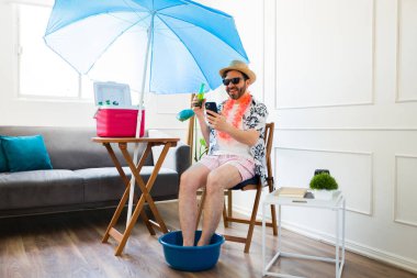 Pedikür yaptırıp, evde gülüp, akıllı telefondan mesajlaşırken sahilde eğlenen heyecanlı bir adam. 