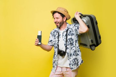 Neşeli beyaz adam yaz tatili için plaja seyahat ediyor. Yanında bavulunu ve pasaportunu da uçak biletleriyle birlikte.