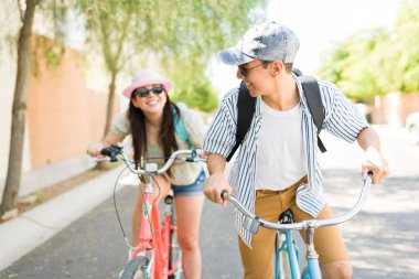Neşeli genç bir kadın ve erkek, sıcak bir yaz gününde dışarıda eski bisikletlerini sürerken eğleniyorlar. 