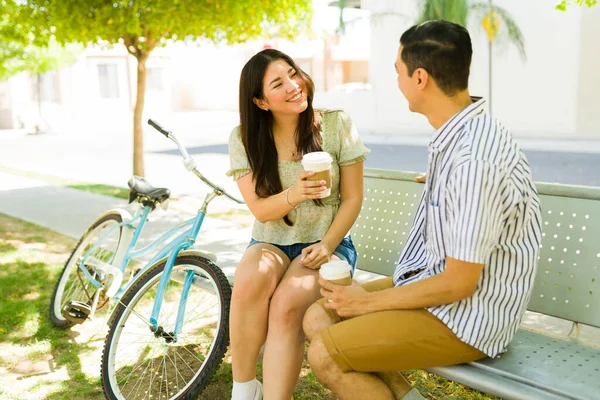 公園でのデート中にコーヒーを飲みながら自転車でベンチに座っている間 彼女のボーイフレンドに笑顔の美しい幸せな女性 — ストック写真