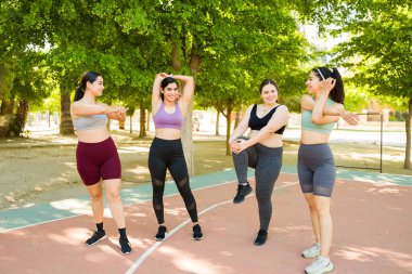 Çeşitli aktif kadın grupları vücut pozitifliğini arttırıyor esniyor ve parkta koşmaya ya da egzersiz yapmaya hazırlanıyor. 