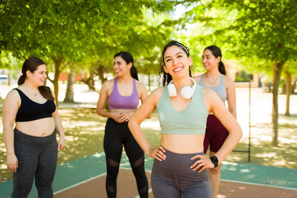 スポーツラテン語の女性とともにヘッドフォンを探しています幸せを実行または運動彼女の多様なグループの女性の友人屋外 — ストック写真