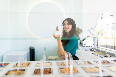 Dondurmacıda çalışan ve tezgahın arkasında durup dondurulmuş yoğurt hazırlayan heyecanlı genç kadın.