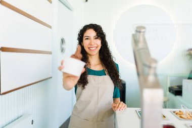 İspanyol neşeli kadın donmuş yoğurt dükkanında lezzetli çikolatalı dondurma satıyor ve çok mutlu görünüyor.