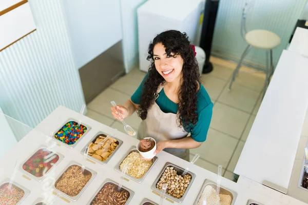 一个有魅力的女人在冰淇淋上加料 在冰淇淋店的柜台上 或者是冷冻酸奶店 她的形象尽收眼底 — 图库照片