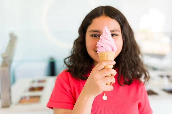 拉丁漂亮女孩把一个冰激凌蛋筒放在她的面前 一边笑着一边享受在糖果店里的购物 — 图库照片