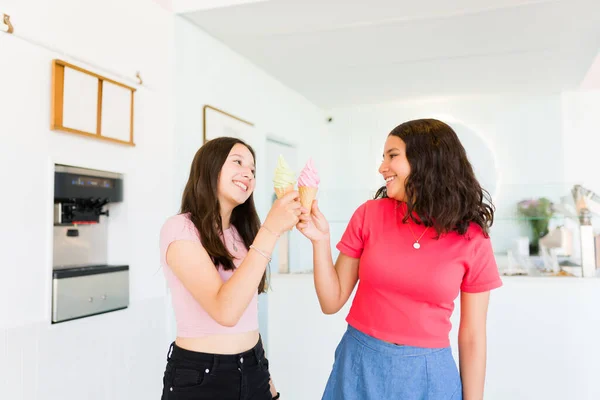アイスクリーム屋でおいしいジェラートコーンを食べながら笑顔で陽気に見ている親友と10代の女の子 — ストック写真