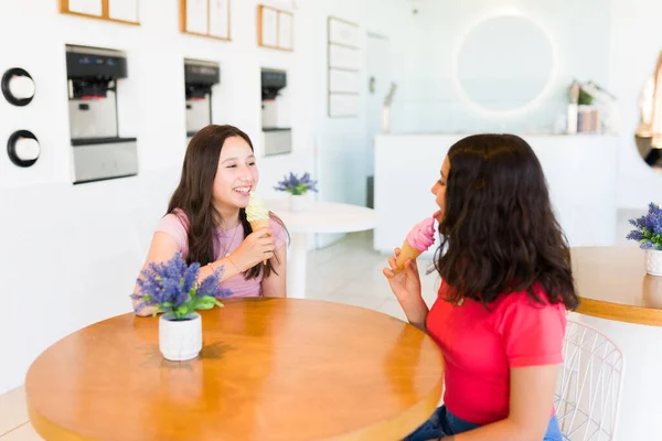 10代の女の子がジェラート店で楽しそうに話しながらアイスクリームコーンを食べながら話して楽しんでいます — ストック写真