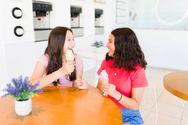 ジェラートコーンを食べながらアイスクリーム屋さんで楽しい時間を過ごしながら笑っている2人の若い10代の女の子幸せそうに見える — ストック写真