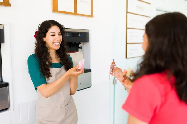 二十多岁的西班牙裔妇女在糖果店工作 为少女提供免费的冰淇淋或冷冻酸奶样品 — 图库照片