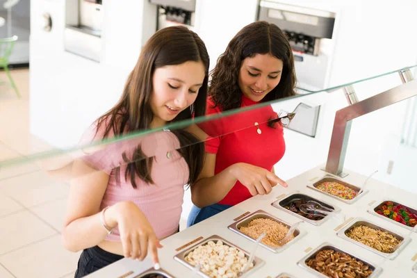 漂亮而快乐的少女和最好的朋友在一起买冰激凌或冷冻酸奶时 会选择美味的配料 — 图库照片