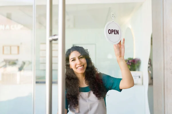 Mexican young woman opening the door of her ice cream shop or business while ready for customers