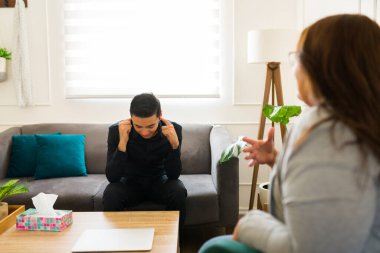 Siyahlı bunalımlı adam kulaklarını kapatıyor ve bir kadın psikoloğa yas tutmasını ve yas tutmasını inkâr ediyor.