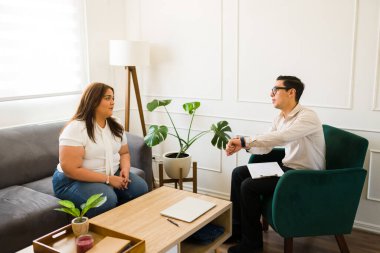 Profesyonel psikolog saatine işaret ediyor ve üzgün hastasına terapi seanslarının bittiğini söylüyor.