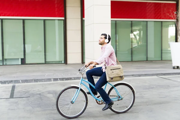 Şehirdeki mutlu iş adamı işe giderken rahat rahat bisikletini sürüyor.