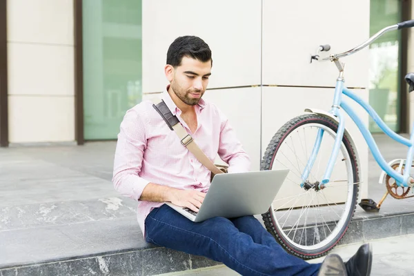自転車に乗って街中のノートパソコンで仕事をしている普通のビジネスマンは幸せそうに見える — ストック写真