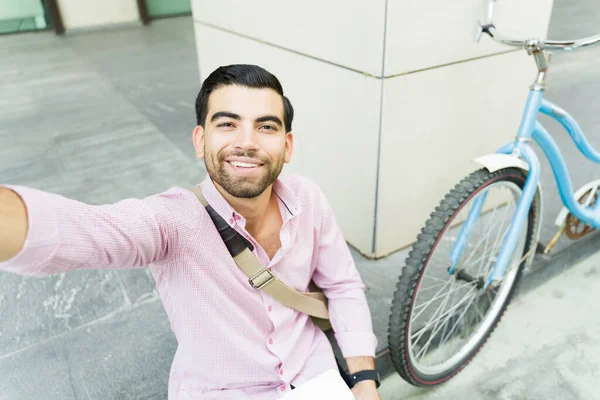 Personal perspective of a handsome man taking a selfie outside his work building with his eco friendly bicycle