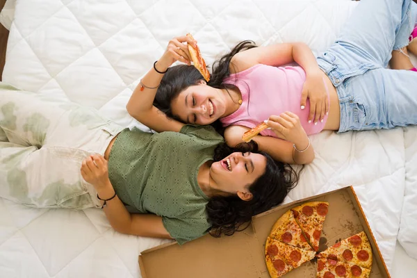 興奮した幸せなティーンエイジャーのトップビューベッドに横たわっている間リラックスしてベッドルームでピザを食べる準備ができている間ハングアウト — ストック写真