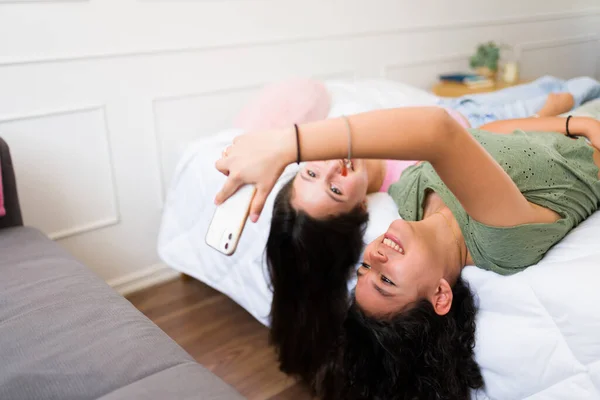 微笑着让青少年最好的朋友在床上放松一下 同时一起出去玩 用手机或社交媒体发短信 — 图库照片