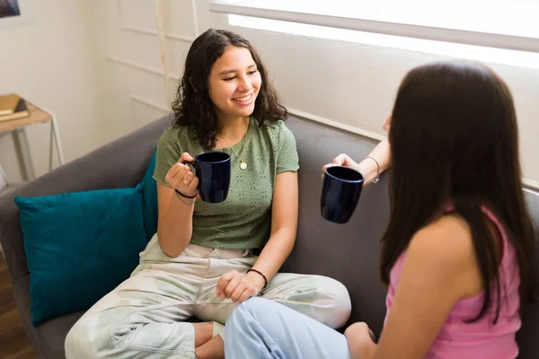 10代の親友が一緒にお茶やチョコレートを飲みながら家で話してリラックスしています — ストック写真