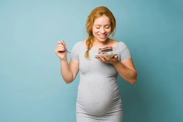 Larında Neşeli Hamile Bir Kadın Stüdyoda Bir Dilim Pastaya Bakıyor — Stok fotoğraf