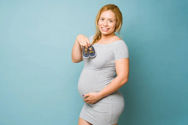Yaşlarda Hamile Güzel Bir Kadın Elinde Bebek Ayakkabısı Mavi Arka — Stok fotoğraf