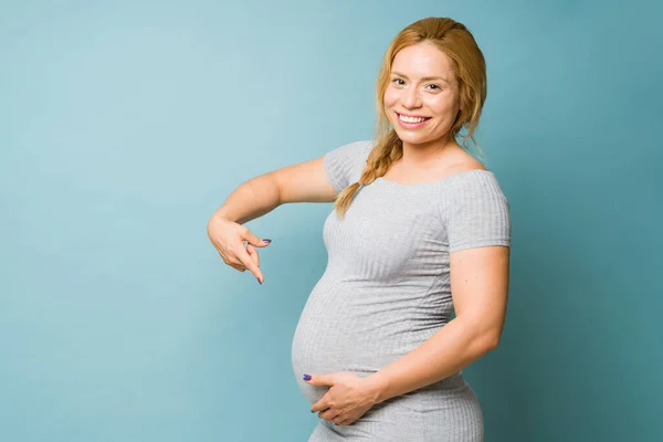 Studyjne Ujęcie Pięknej Podekscytowanej Kobiety Ciąży Trzydziestce Wskazującej Brzuch — Zdjęcie stockowe