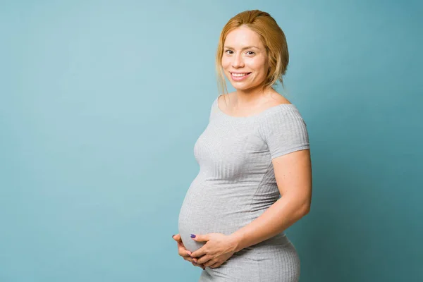 Portret Pięknej Kobiety Ciąży Trzydziestce Stojącej Niebieskim Tle Studiu — Zdjęcie stockowe