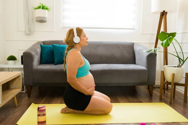 Güzel Hamile Bir Kadın Kulaklık Takıyor Evde Oturup Meditasyon Yapıyor — Stok fotoğraf