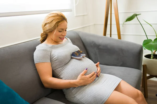 Cute Kobieta Ciąży Dotykając Jej Brzuch Podczas Patrząc Parę Butów — Zdjęcie stockowe