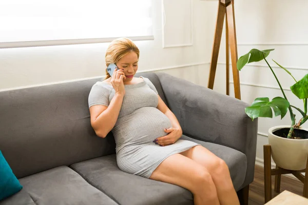 若い妊婦は医者に電話しながら仕事をして痛みを感じる — ストック写真