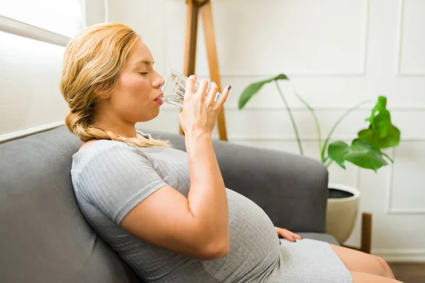 妊婦は家のガラスから水を飲む — ストック写真