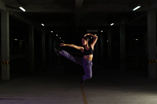 길거리 댄서가 어두운 주차장에서 공중으로 뛰어오르면서 — 스톡 사진