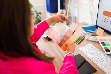 Profesyonel tasarımcı yeni bir tasarım üzerinde çalışırken ofis masasındaki renk örneklerine bakıyor.
