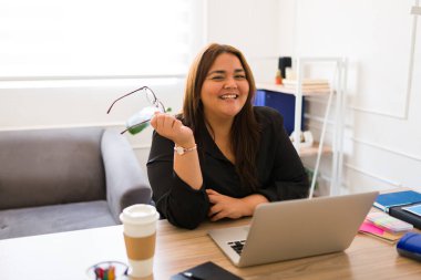 Neşeli şişman satış müdürü gülerek ve eğlenirken gözlüğünü çıkarıyor ve ofiste mutlu görünüyor.