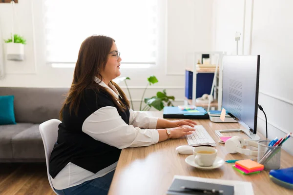 プラスサイズのプロの女性は 営業担当者として働いている間 彼女のオフィスでコンピュータ上で忙しいタイプ — ストック写真