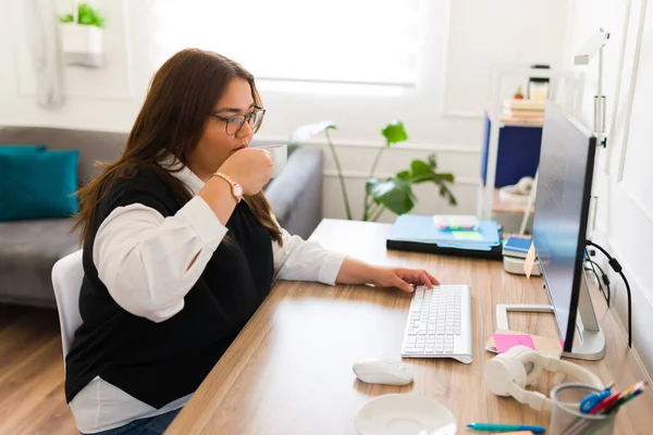 仕事中にコンピュータの前に座っている間 美しい大企業の女性は彼女の作業机でコーヒーを飲む — ストック写真
