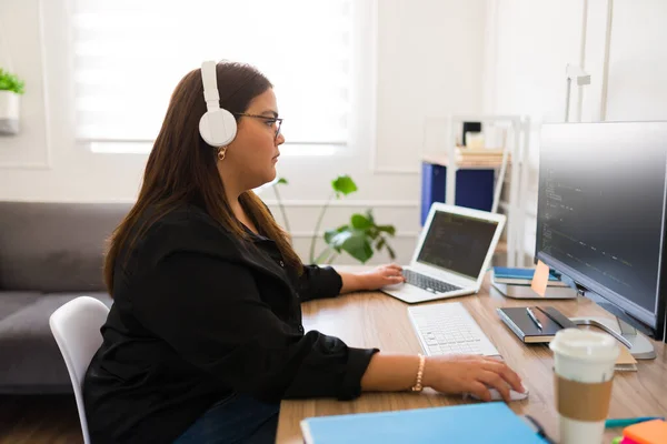 オフィスのヘッドフォンで新しいソフトウェアをコーディングするコンピュータ上で働く集中脂肪の女性エンジニアやプログラマー — ストック写真