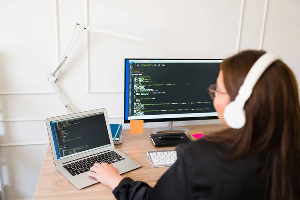 ソフトウェアをコーディングしながら コンピュータやラップトップを使用してヘッドフォンで太った女性プログラマーやエンジニアの背面図 — ストック写真