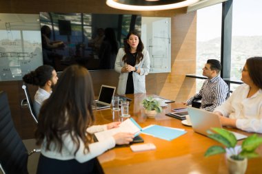 Çekici Asyalı iş kadını ofis konferans odasında yaptığı toplantıda ekiple yeni stratejiler paylaşıyor.