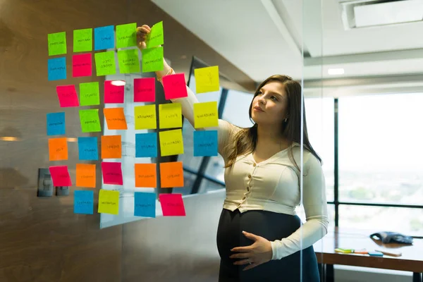 Беременная Деловая Женщина Вешает Красочные Липкие Заметки Стеклянную Стену Офисе — стоковое фото