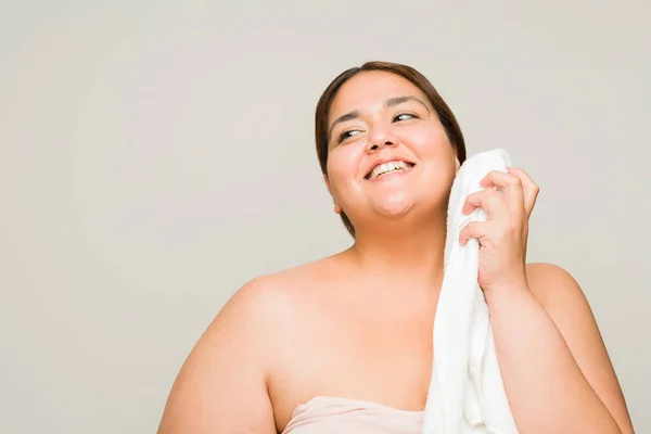 リラックスした幸せなプラスサイズの女性洗浄とクリーニング彼女の顔でタオルを持っています彼女のスキンケアルーチンの後にスパ日 — ストック写真