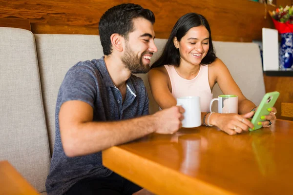 微笑着迷人的男女在咖啡店里约会 一边用智能手机发短信 一边显得快乐 — 图库照片