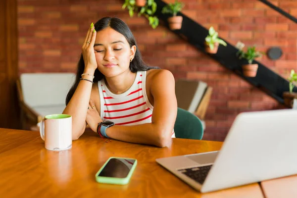 厌倦了的年轻女性在笔记本电脑上做自由职业工作时感到困倦和疲倦 — 图库照片