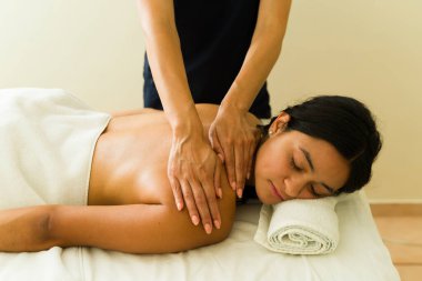 Rahatlamış güzel Latin kadın sağlık merkezinde dinleniyor. Terapi görüyor ve sırt masajı yaptırıyor.