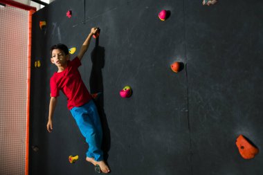 Eğlenirken ve eğlenirken çocuklarla kaya tırmanışı yaparken gülümseyen Latin çocuk.