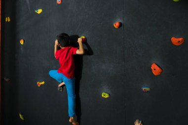 Kaya tırmanışında arka kapıdan görülen ve boş zamanlarında eğlenen genç çocuk.