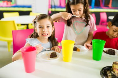Çocuk parkında doğum günü pastası beklerken pasta yiyip gülümseyen güzel mutlu çocuklar. 