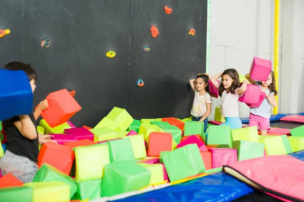 兴奋的小孩在室内操场上玩泡沫立方体的游戏 开心地笑着 — 图库照片
