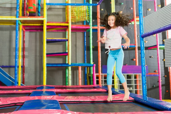 Heyecanlı Latin çocuk trambolin bölgesinde zıplıyor ve gülüyor kapalı alanlarda eğleniyor.